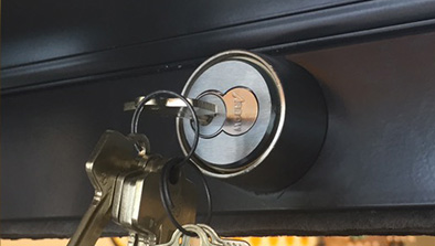 A metal door lock being checked for functionality through inserting keys.